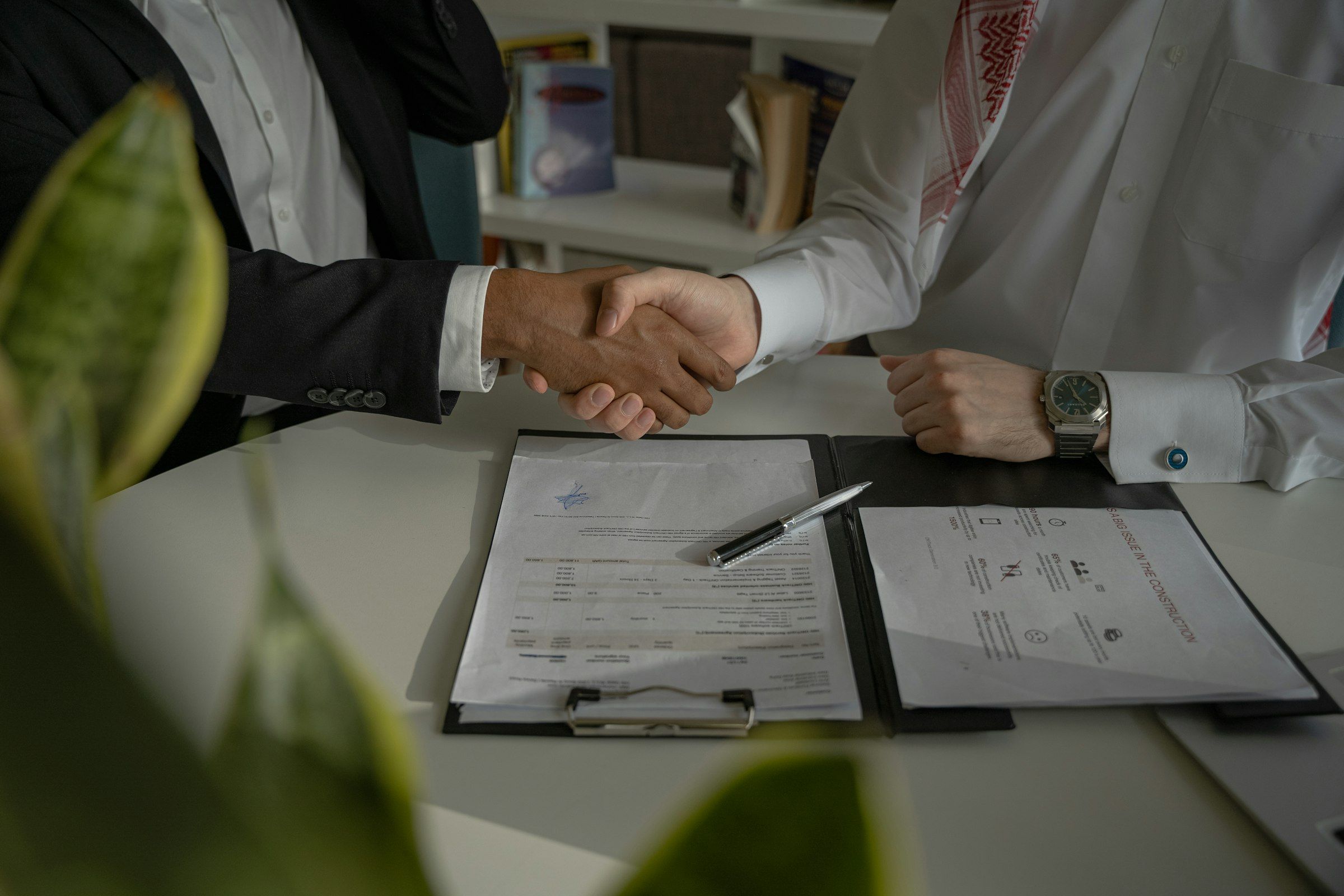 Dos personas se dan la mano sobre un contrato en una mesa