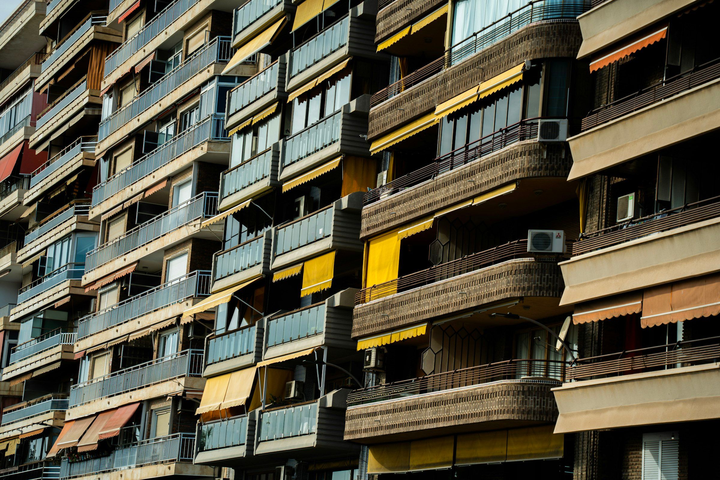 Bloque de pisos con balcones, toldos de colores y aparatos de aire acondicionado en la fachada