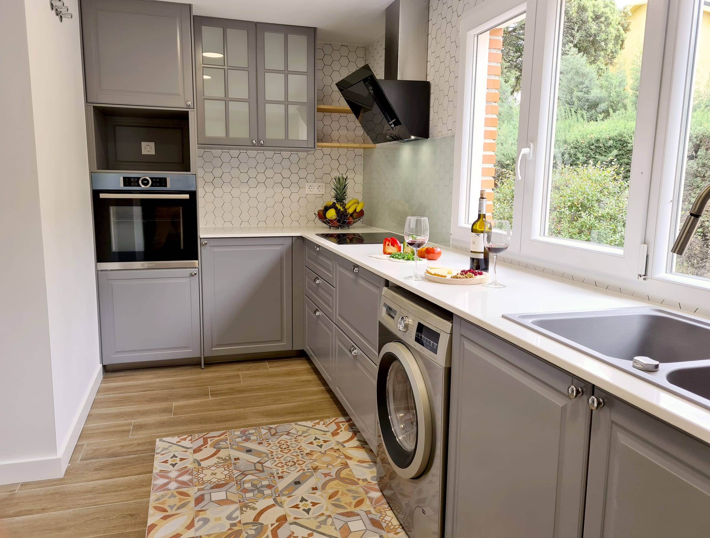 Cocina reformada en gris con encimera blanca y ventanas al jardín