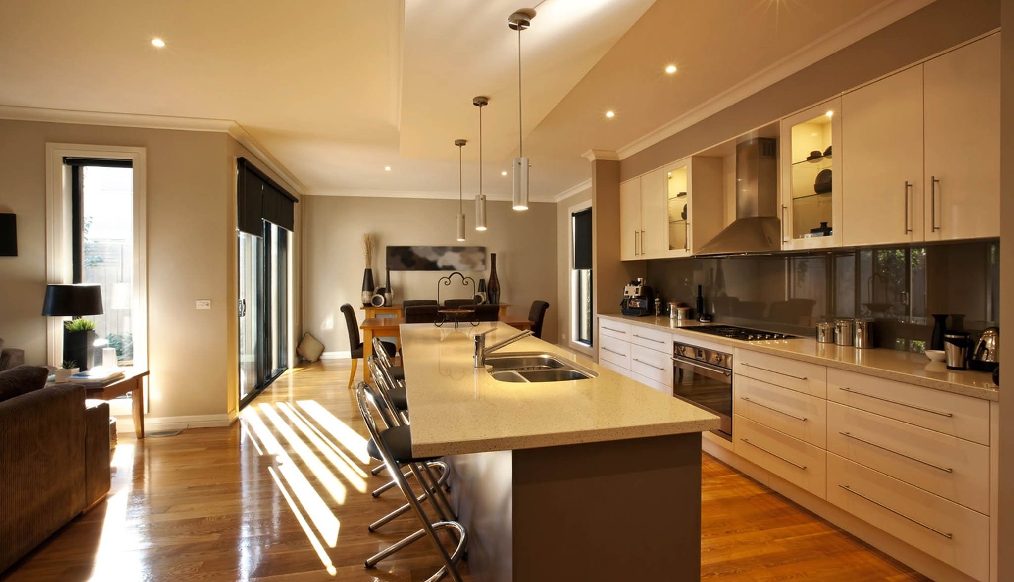 Cocina con isla larga abierta al salón y al comedor, con suelo de madera