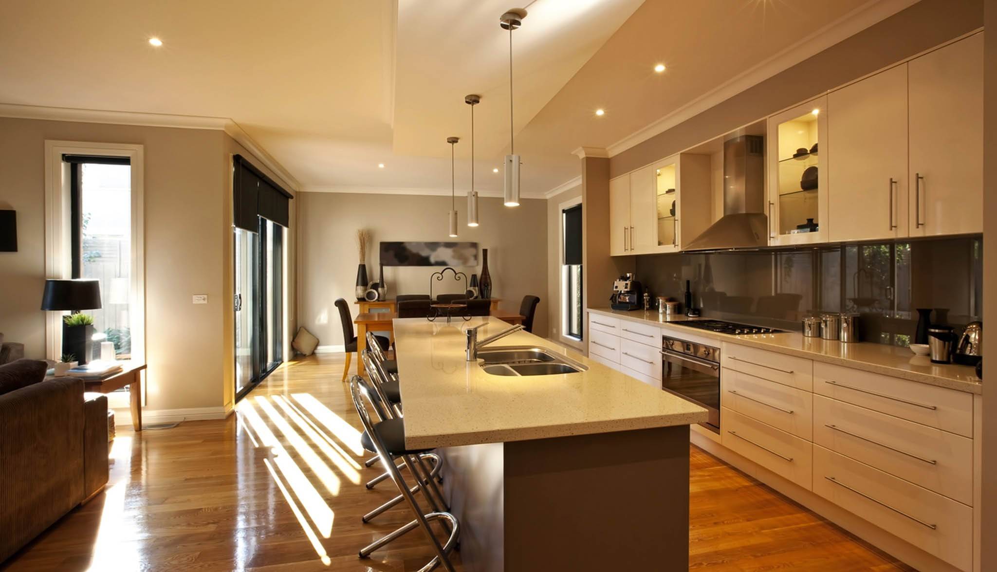 Cocina con isla larga abierta al salón y al comedor, con suelo de madera
