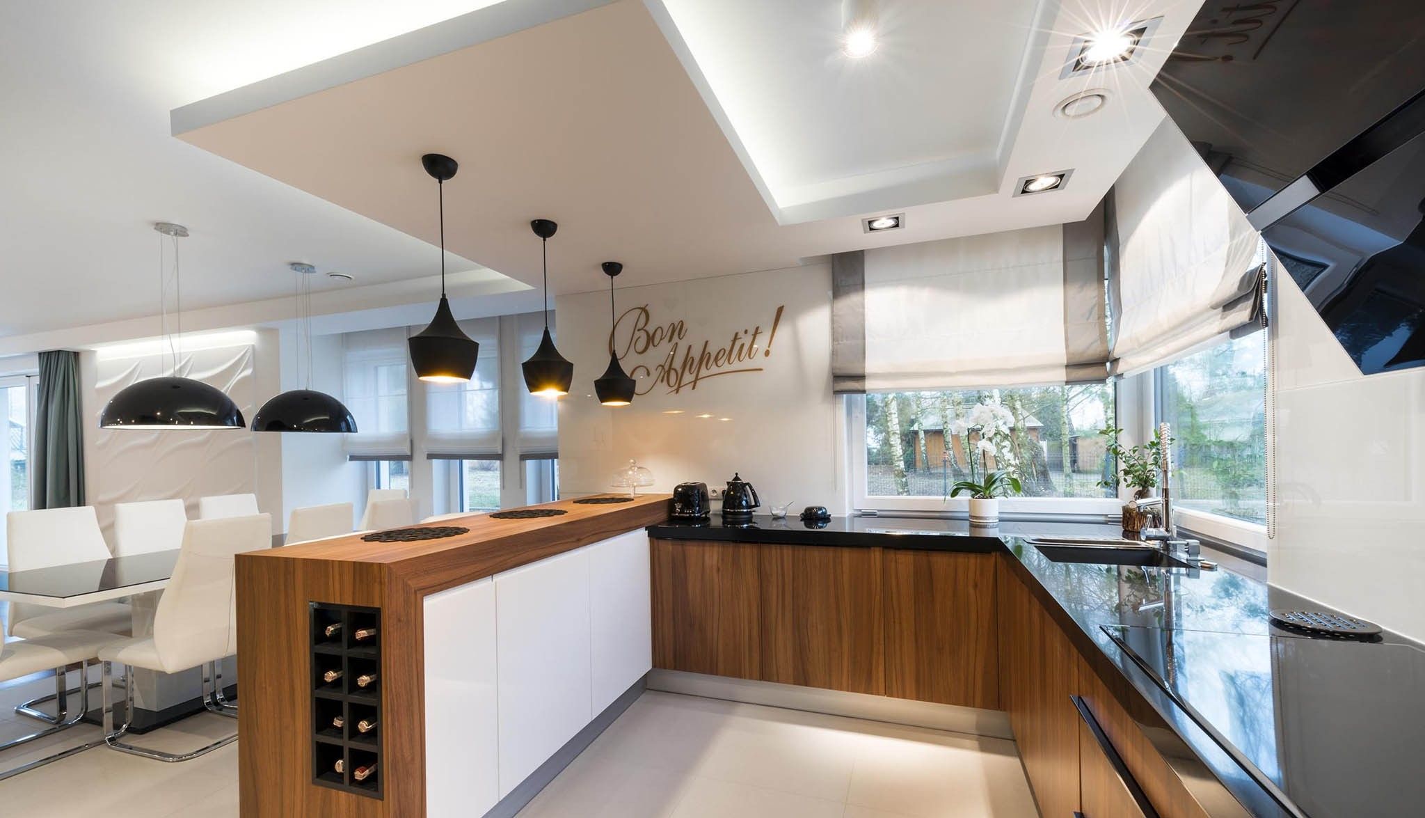 Cocina reformada con muebles de madera, barra con botellero y techo con luz indirecta