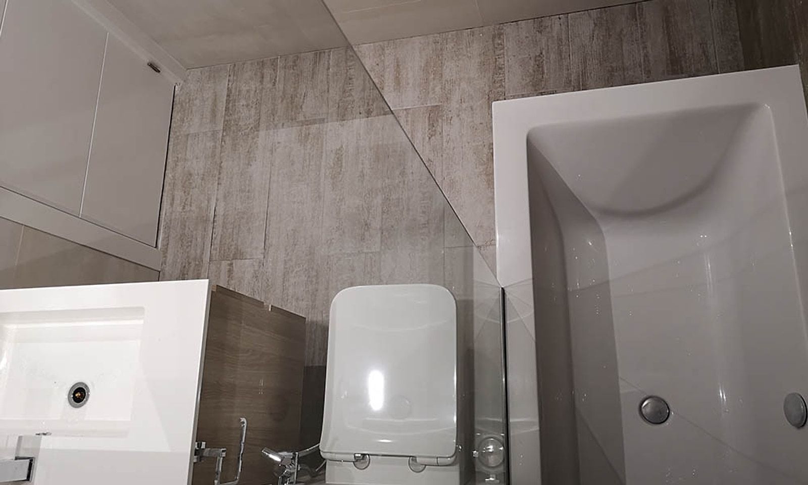 Baño del loft con bañera, inodoro suspendido y lavabo sobre mueble de madera
