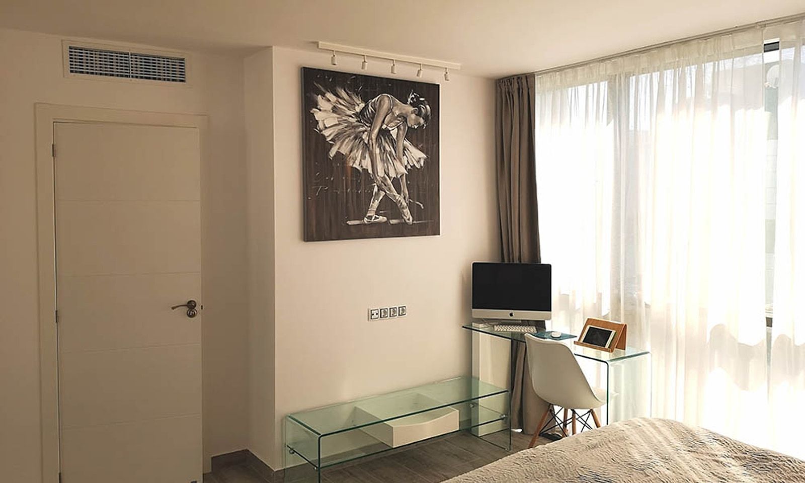 Dormitorio del loft con cortinas, escritorio de cristal y la rejilla del aire en lo alto de la pared