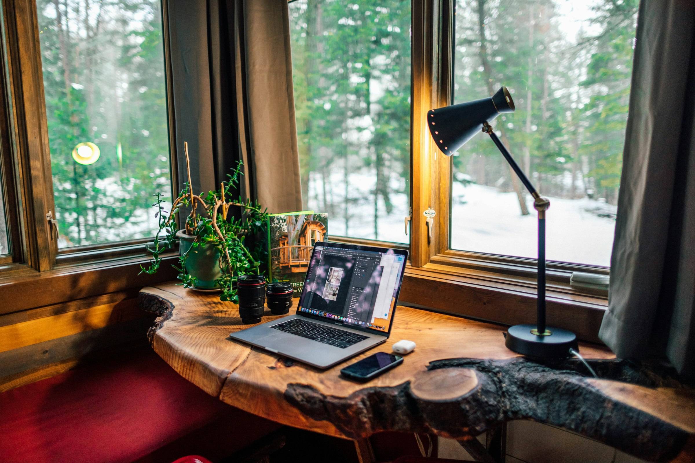 Escritorio de madera con un portátil junto a una ventana