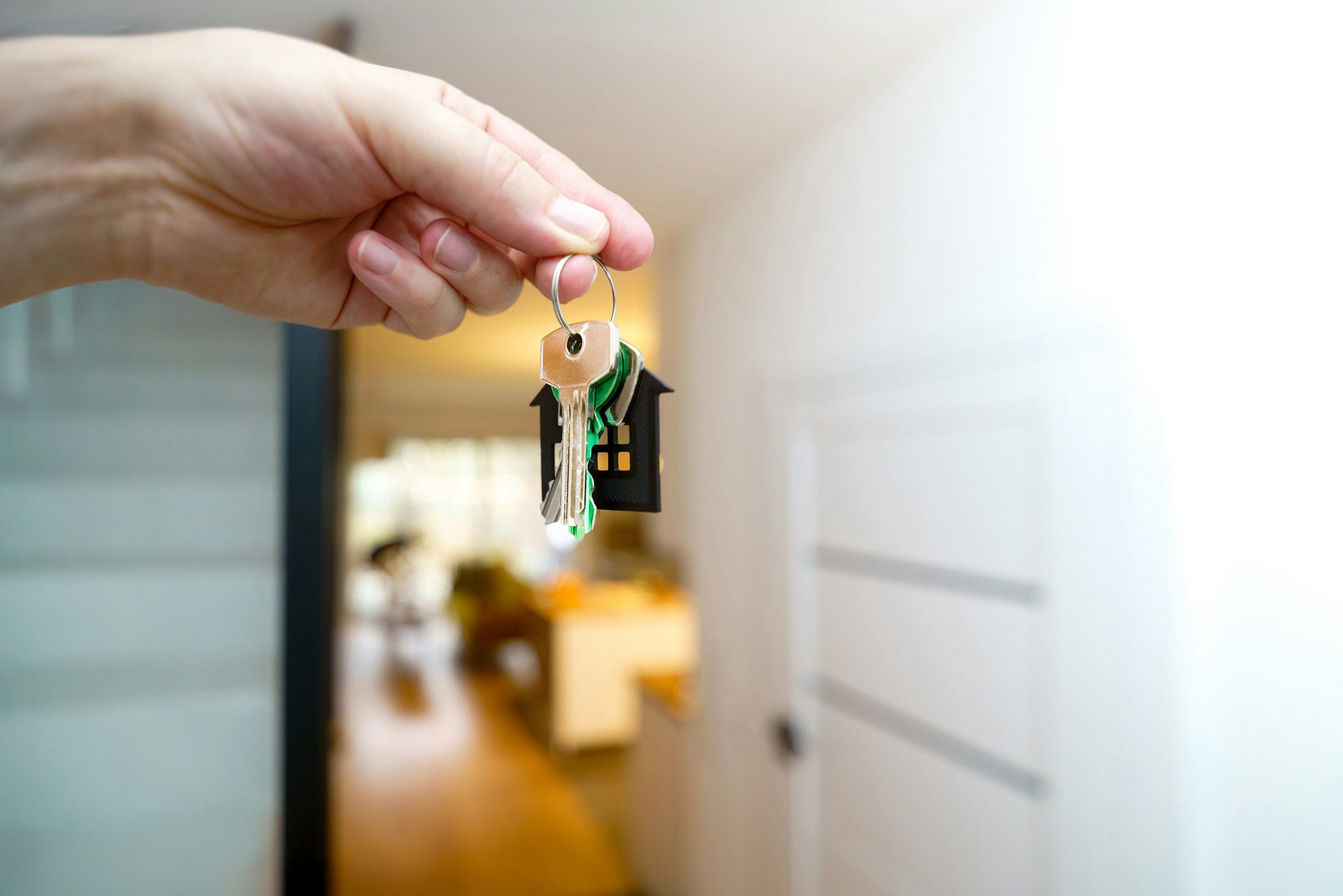 Mano que sostiene unas llaves con llavero de casa en un piso luminoso