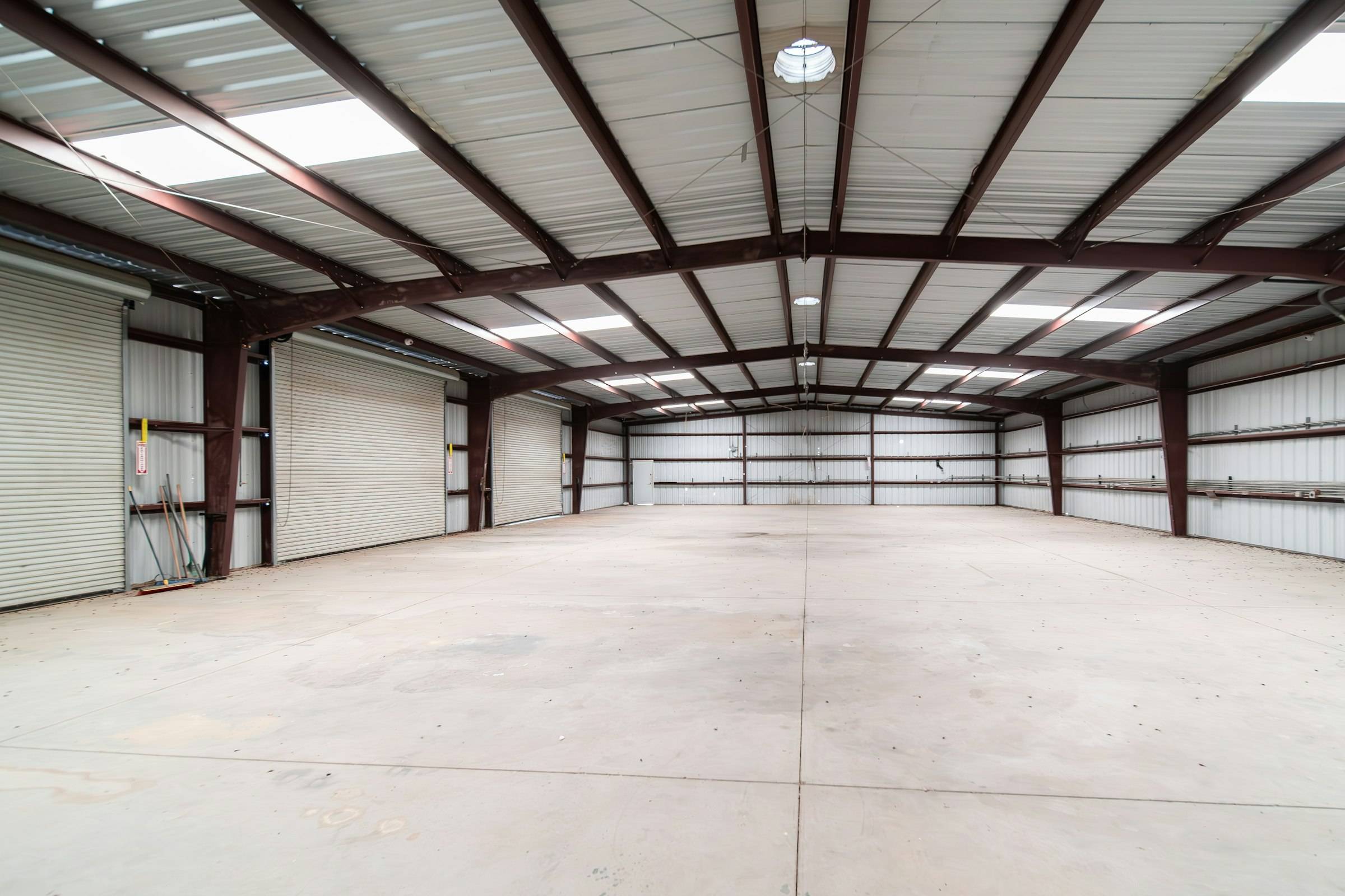 Nave industrial diáfana con pórticos de estructura metálica, lucernarios en la cubierta y puertas enrollables
