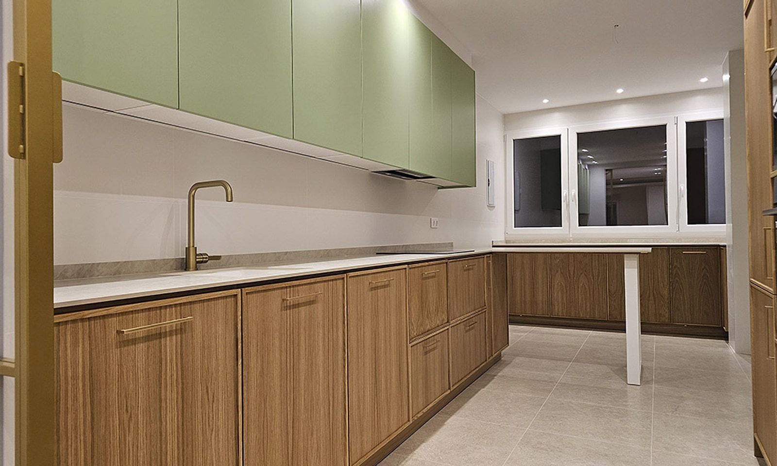 Cocina con muebles de madera y armarios altos en verde en un piso reformado