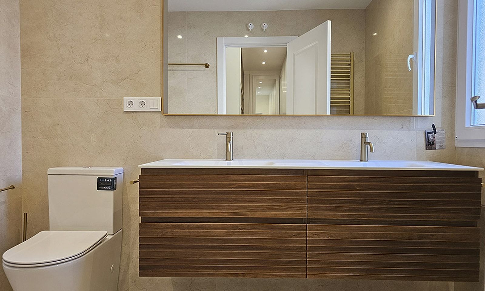 Baño principal con mueble de madera a medida, dos lavabos y espejo grande con marco dorado
