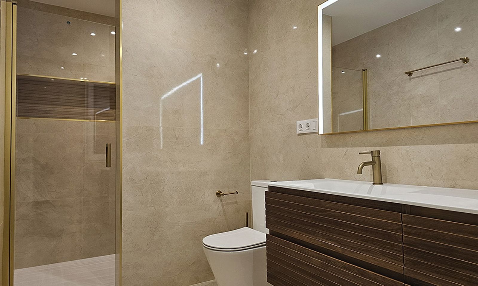 Baño con ducha de mampara, porcelánico claro y mueble de madera con espejo iluminado