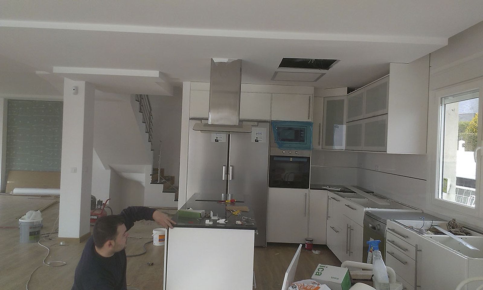 Planta baja de un chalet en obra, con la cocina a medio montar y un operario trabajando