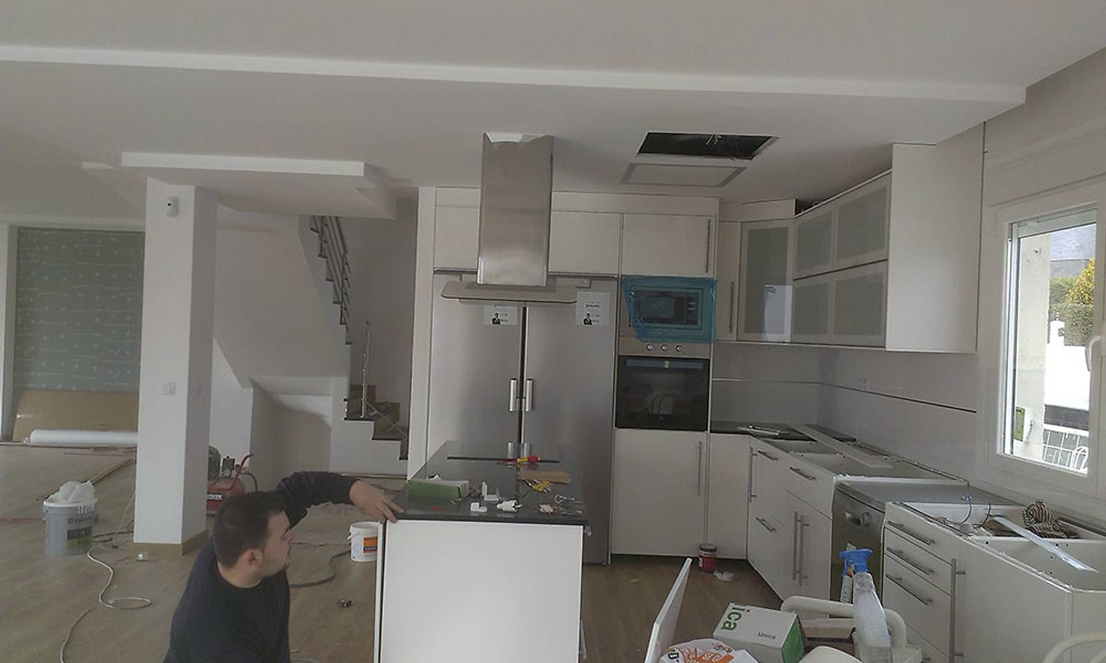 Planta baja de un chalet en obra, con la cocina a medio montar y un operario trabajando
