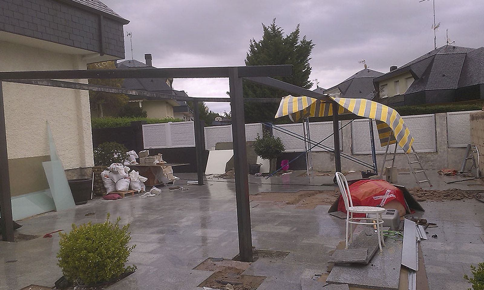 Jardín de un chalet en obra, con la estructura del porche y material por el suelo
