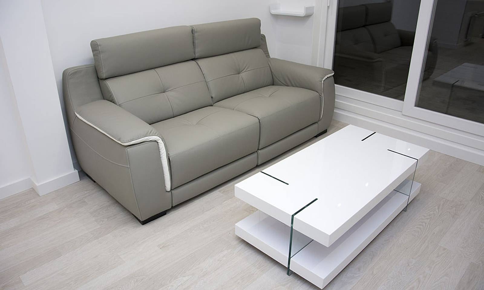 Salón con sofá gris, mesa de centro blanca y tarima clara