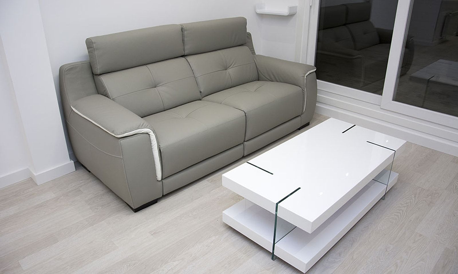 Salón con sofá gris, mesa de centro blanca y tarima clara