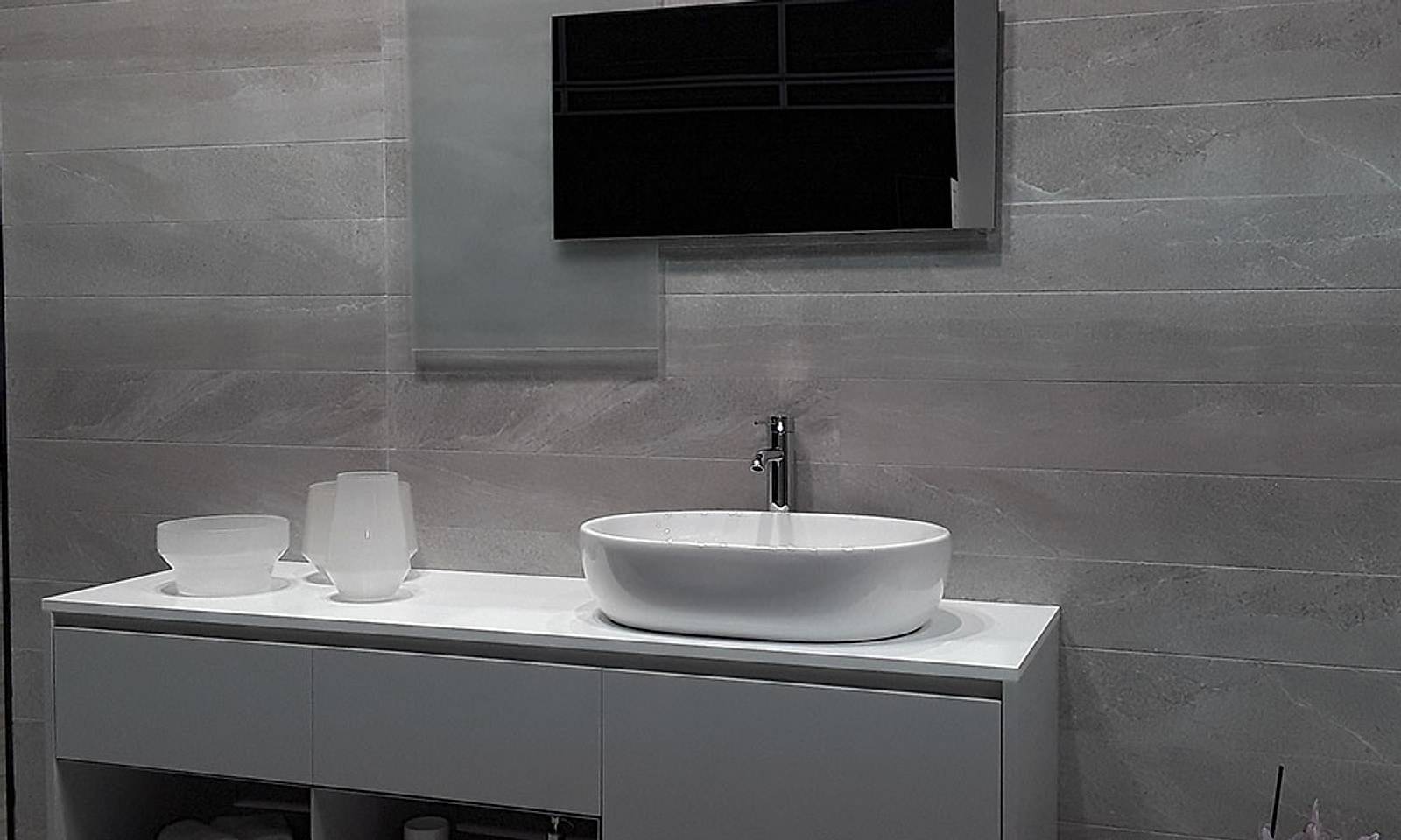 Lavabo sobre encimera blanca con porcelánico gris de gran formato en la pared
