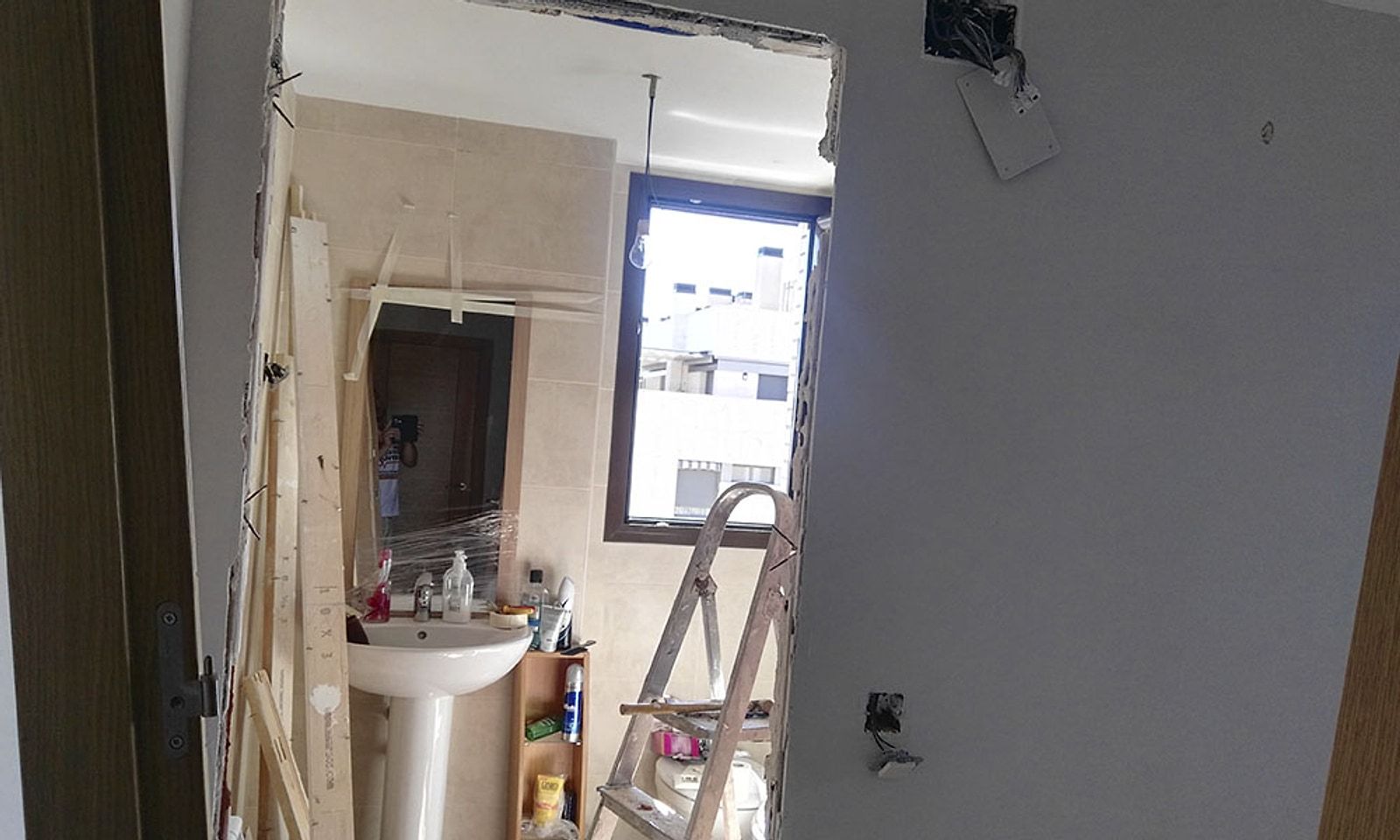 Baño en obra con la puerta desmontada y un lavabo de pie antiguo