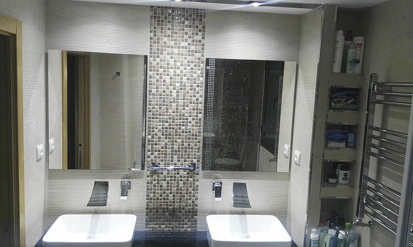 El mismo baño terminado, con dos lavabos, una franja de gresite y un toallero de acero