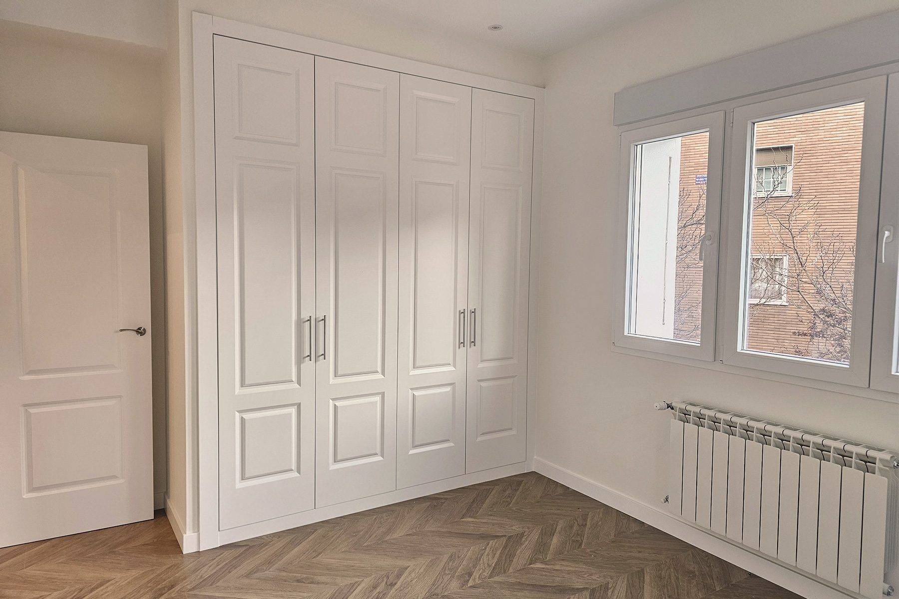 Dormitorio con armario empotrado de puertas blancas de cuarterones y ventana