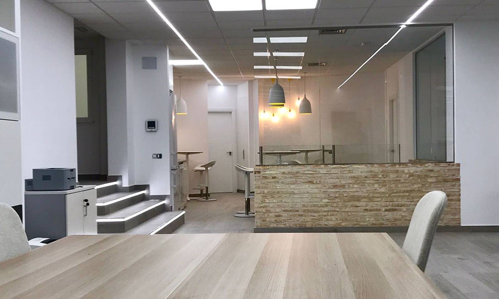 Oficina con la escalera iluminada y un mostrador de ladrillo rústico
