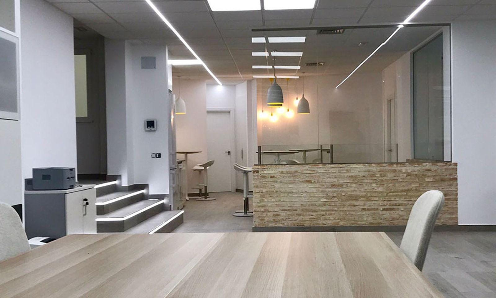 Oficina con la escalera iluminada y un mostrador de ladrillo rústico