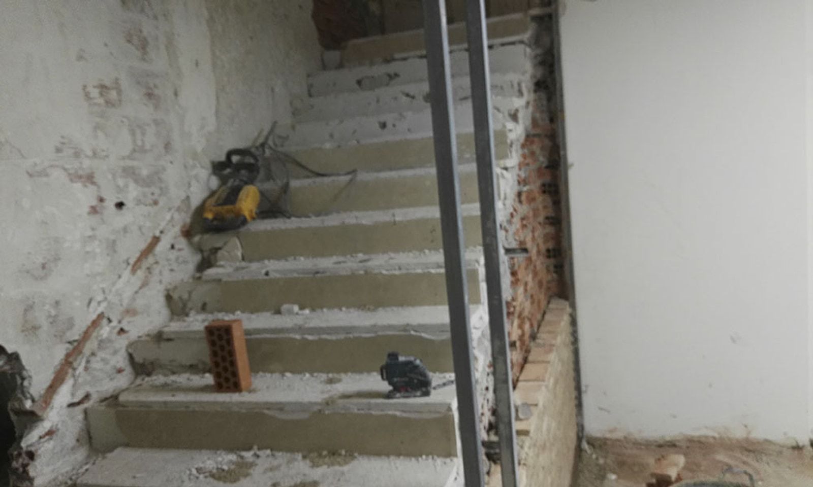 Escalera de una oficina en obra, con los peldaños de hormigón y la pared picada
