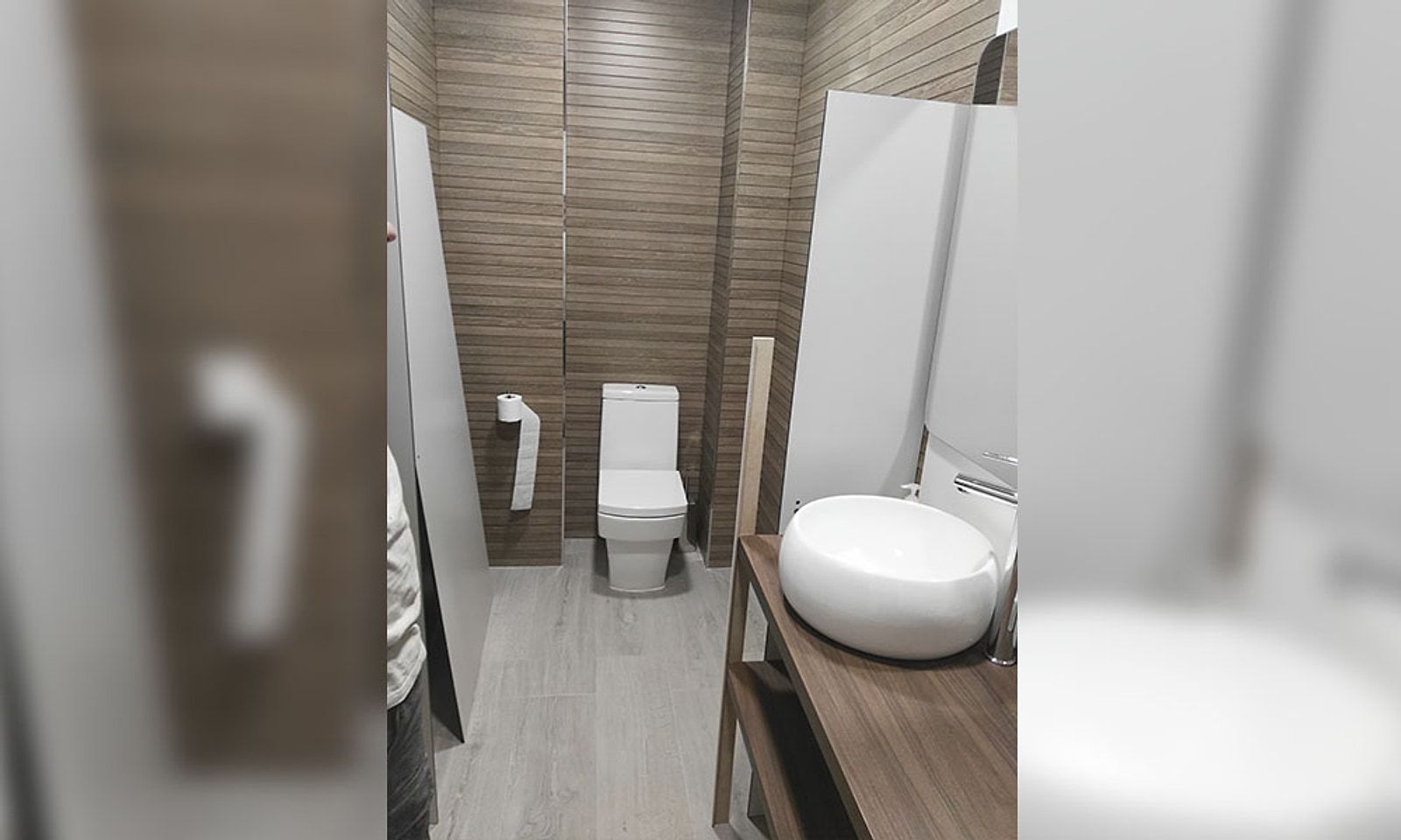 El mismo aseo terminado, con inodoro, lavabo sobre encimera de madera y alicatado de listones