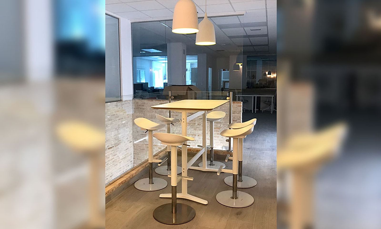 La misma zona terminada, como office con mesas altas, taburetes y lámparas colgantes