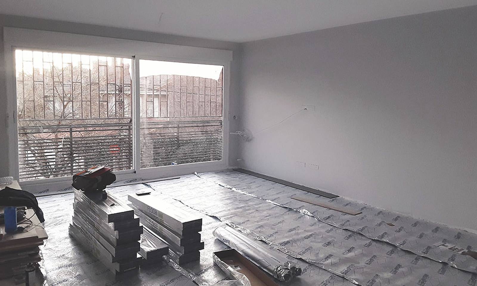 Salón del piso durante la obra, con la lámina aislante en el suelo y las cajas de tarima apiladas