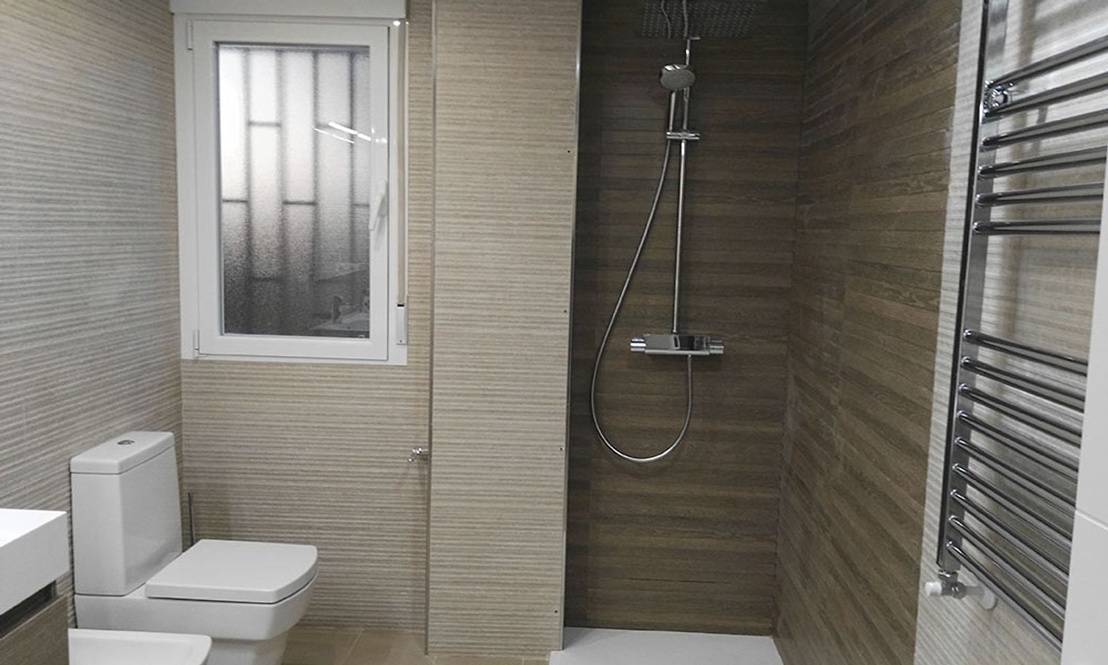 Baño con ducha, alicatado en tonos madera, inodoro y toallero