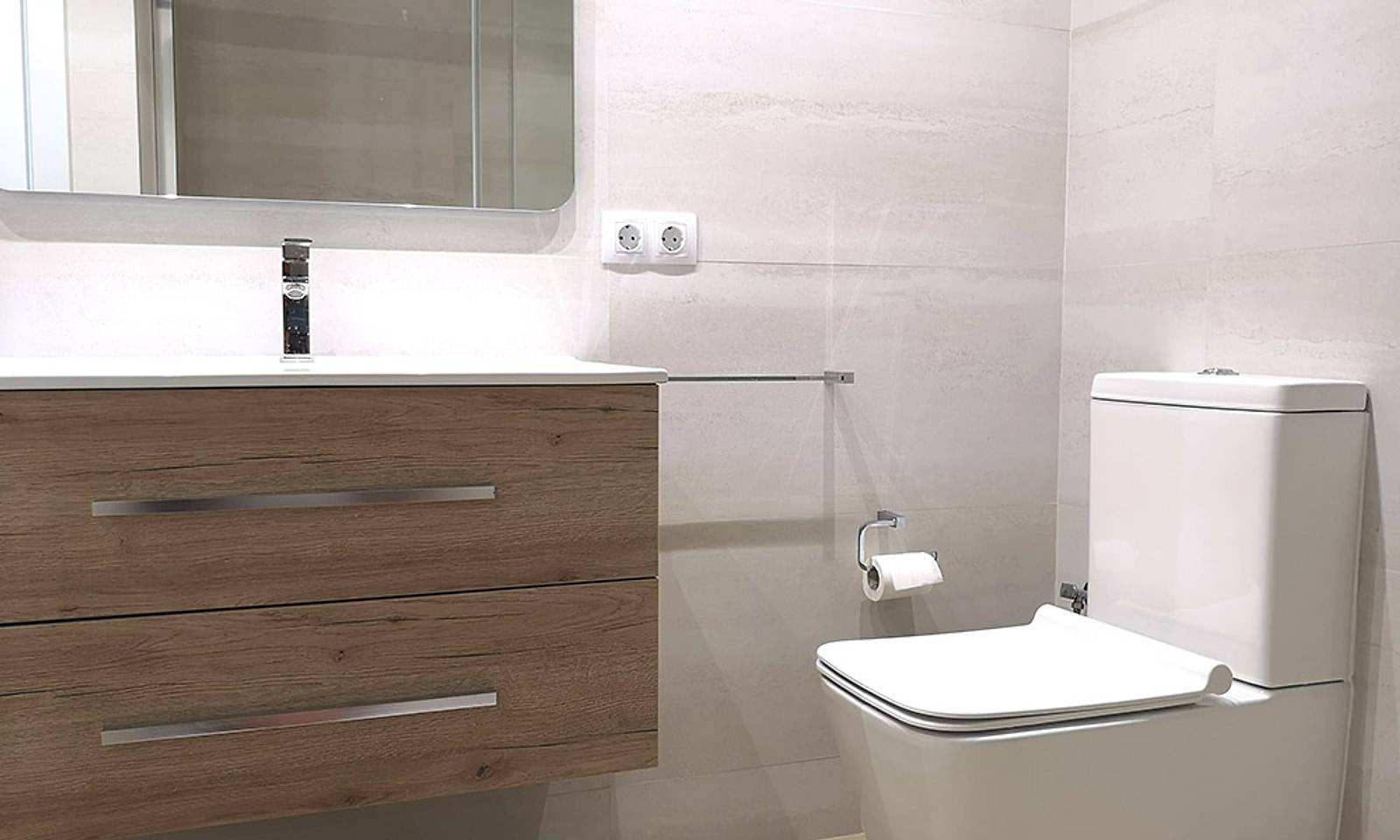Baño con mueble suspendido de madera, espejo e inodoro