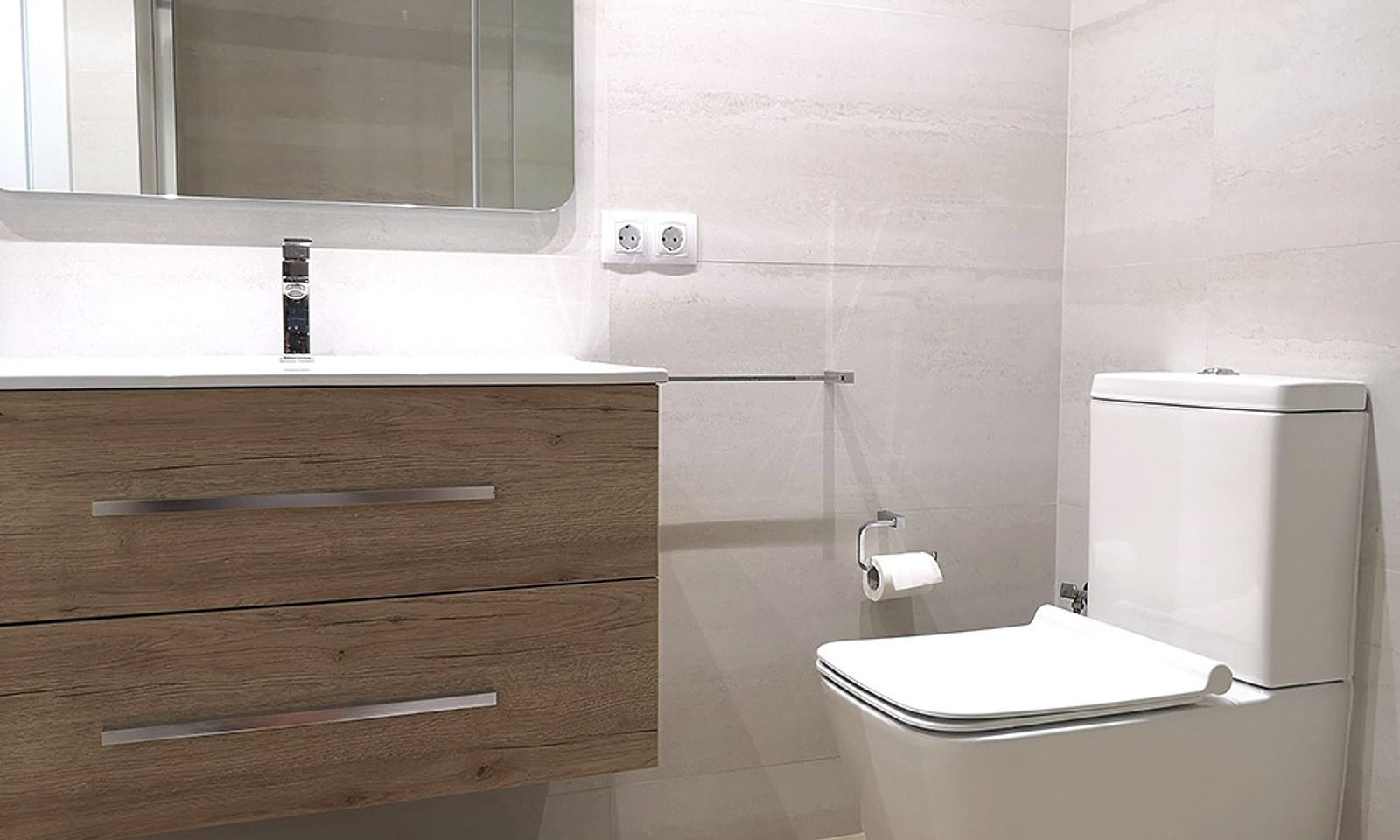 Baño con mueble suspendido de madera, espejo e inodoro