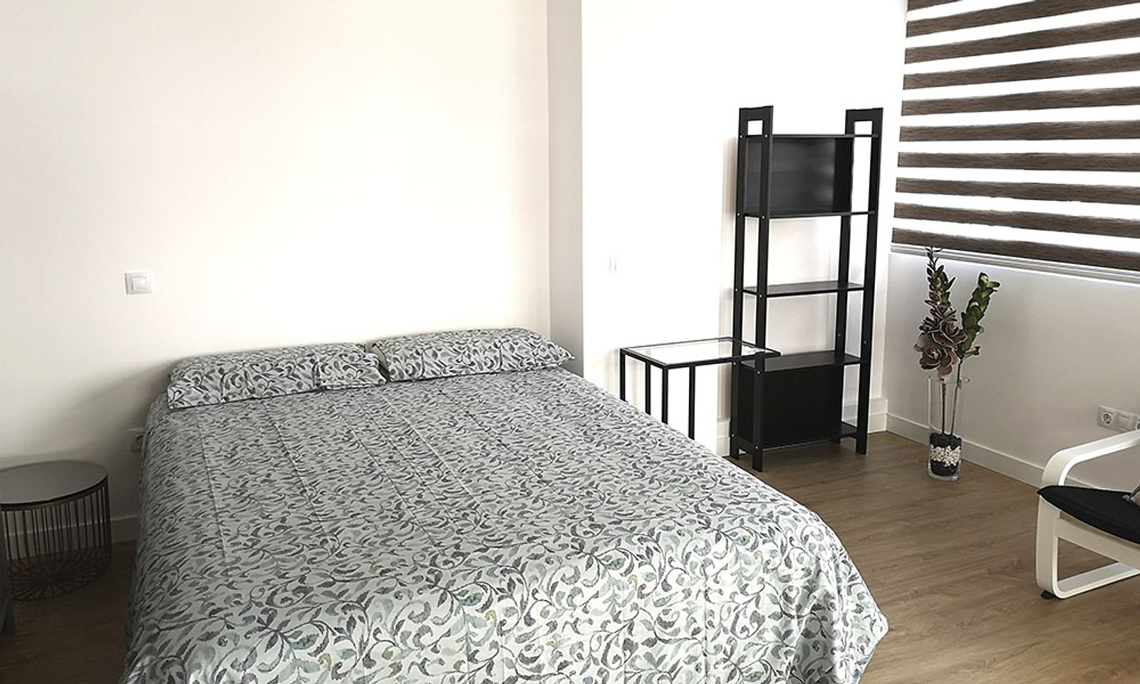 Dormitorio con cama de matrimonio, tarima y estores en la ventana