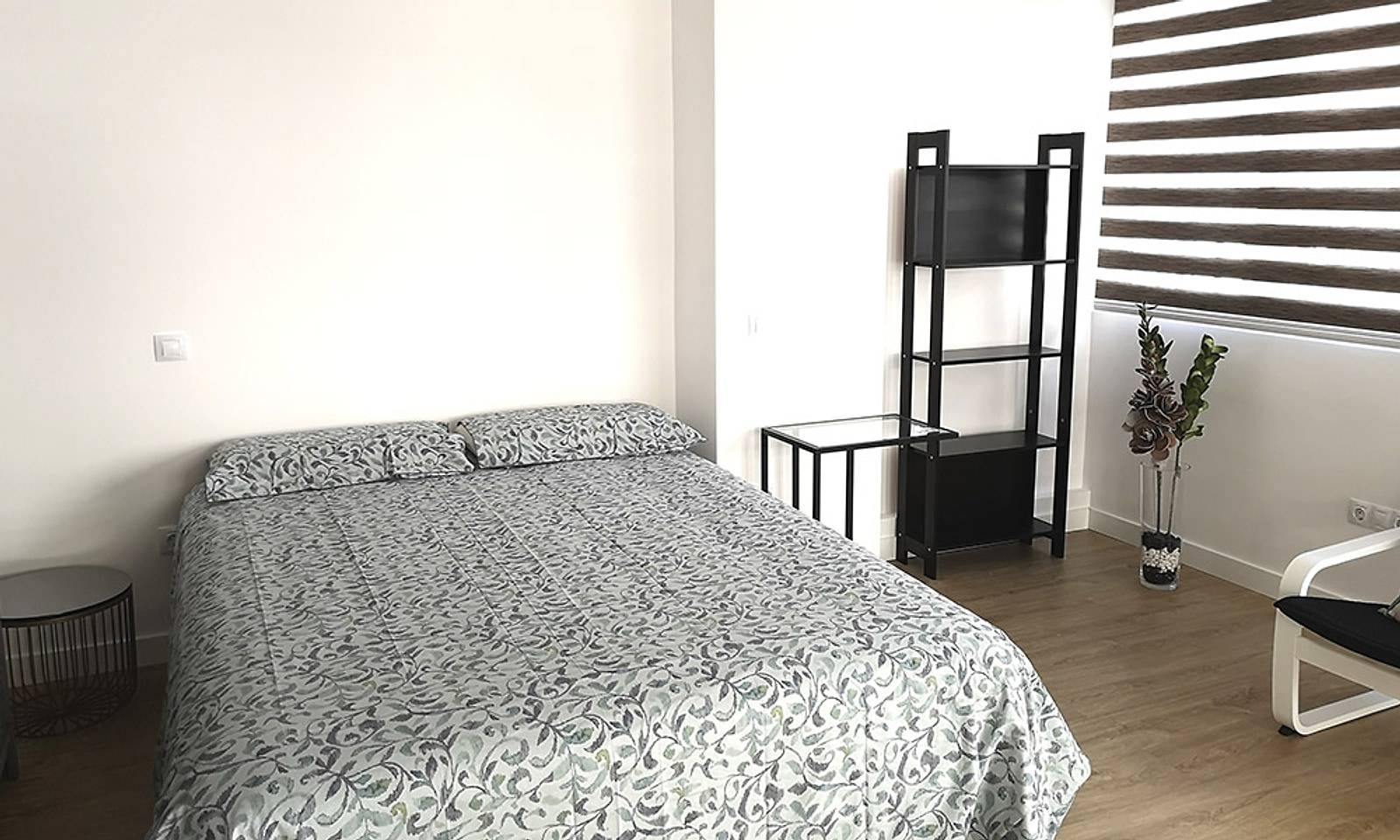 Dormitorio con cama de matrimonio, tarima y estores en la ventana