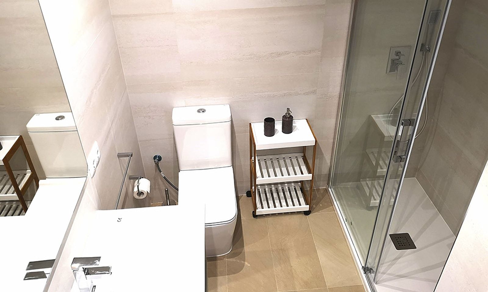 El mismo baño reformado, con alicatado claro, inodoro nuevo y ducha con mampara