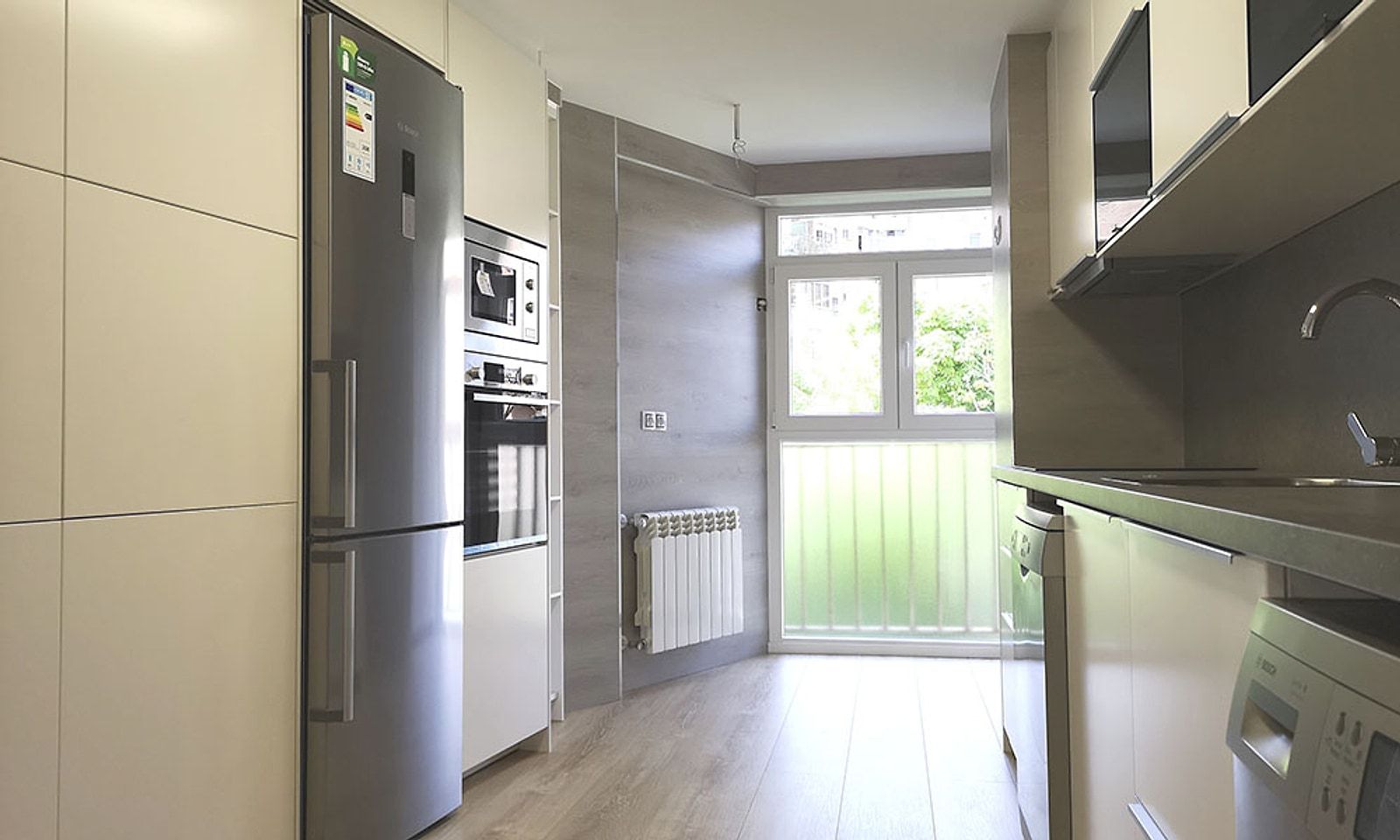 Cocina con muebles a medida, frigorífico y horno en columna, y la terraza al fondo
