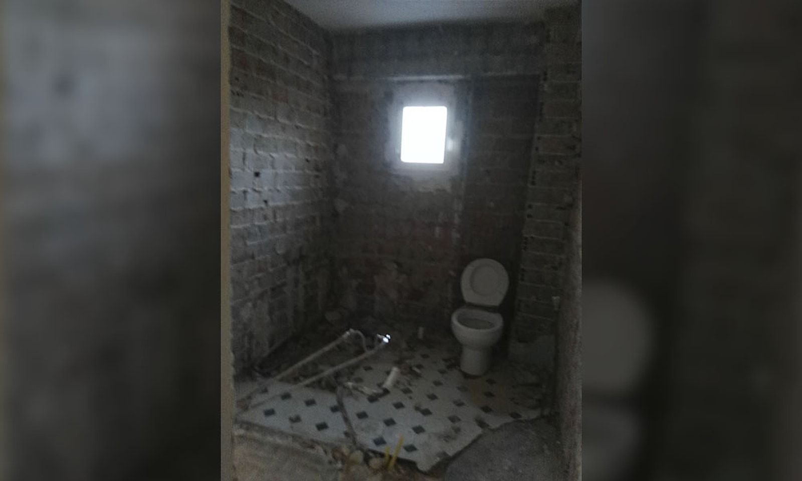 Baño en obra con las paredes de ladrillo a la vista y el suelo levantado