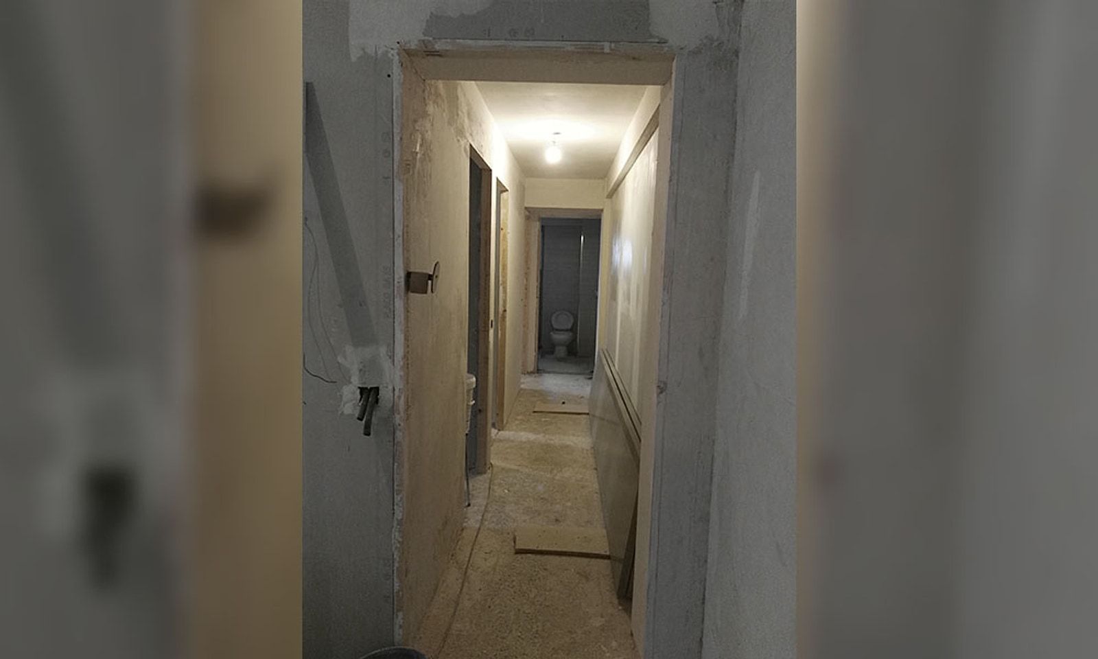 Pasillo de un piso en obra, con las paredes sin terminar