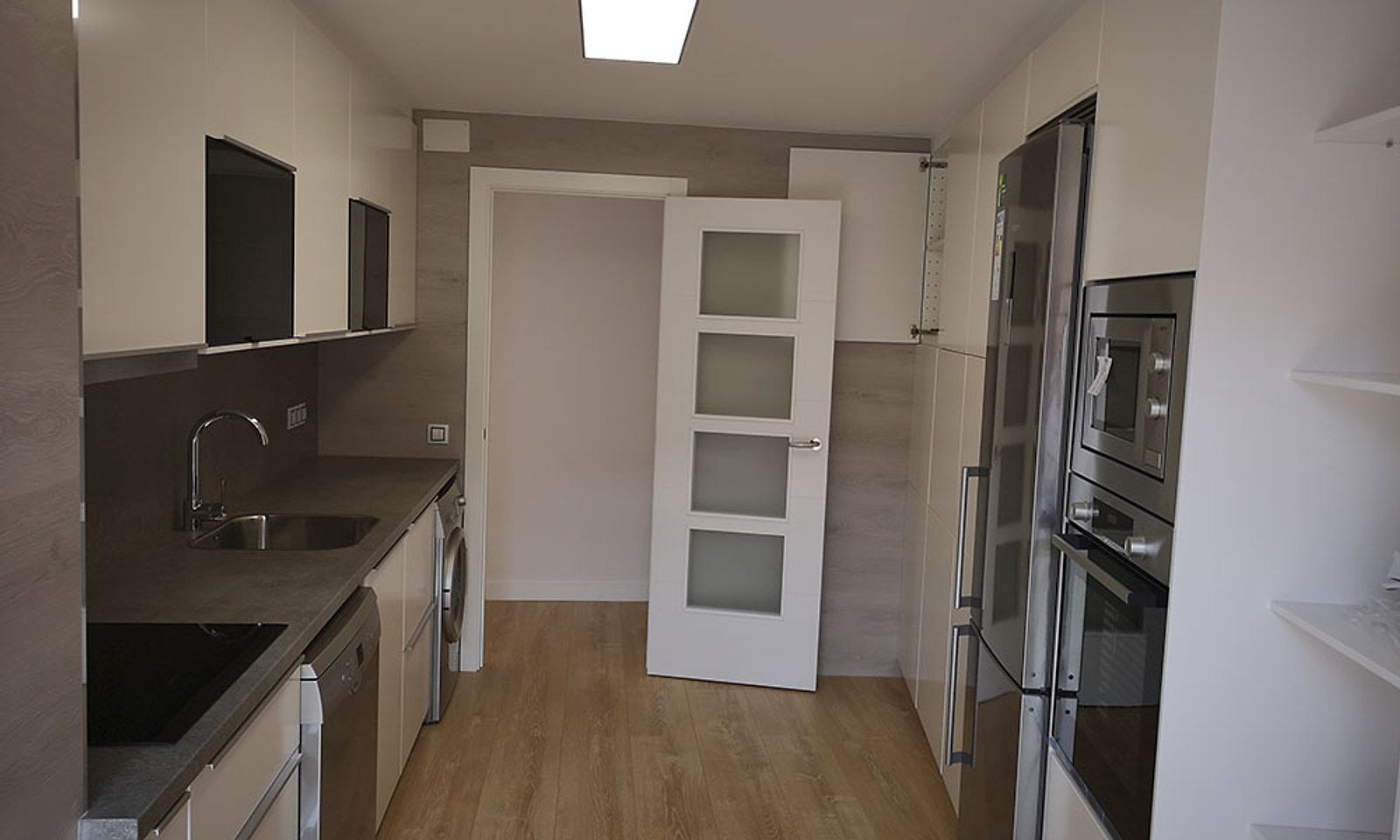 Cocina del piso terminada, con muebles a medida, horno en columna y una puerta acristalada