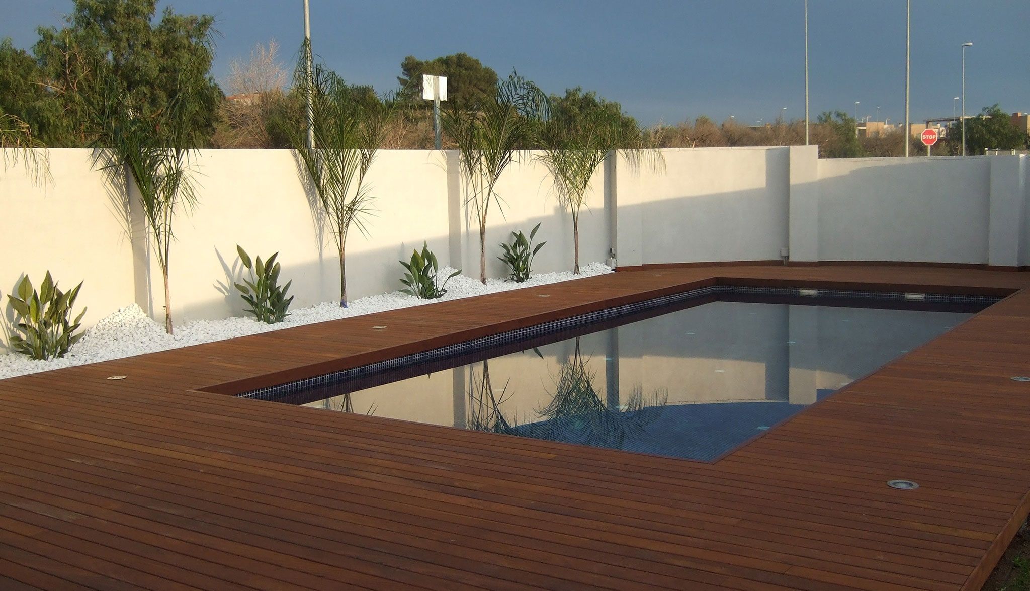 Piscina con tarima de madera en el jardín de un chalet
