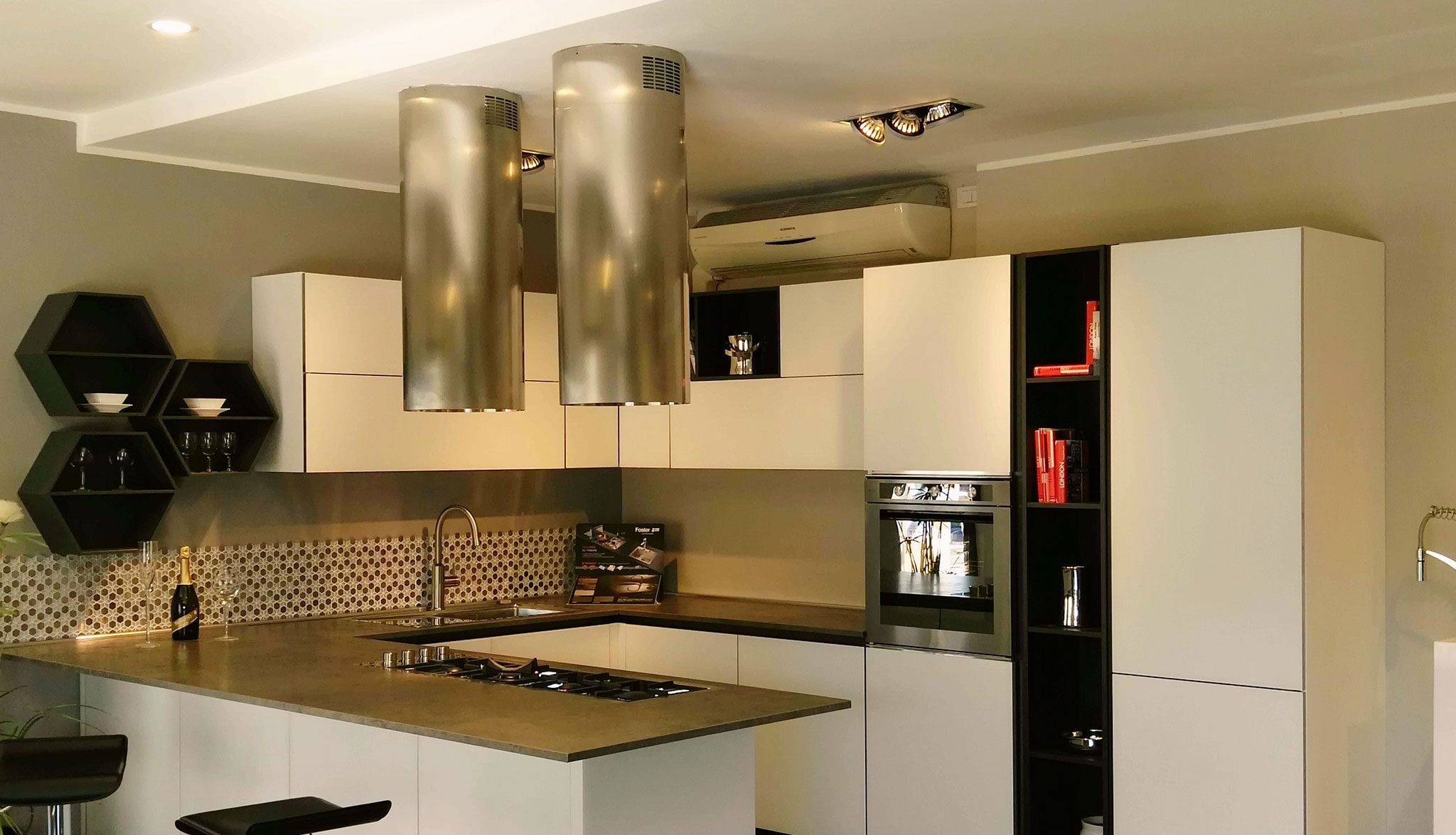 Cocina reformada con península, encimera oscura y campanas cilíndricas