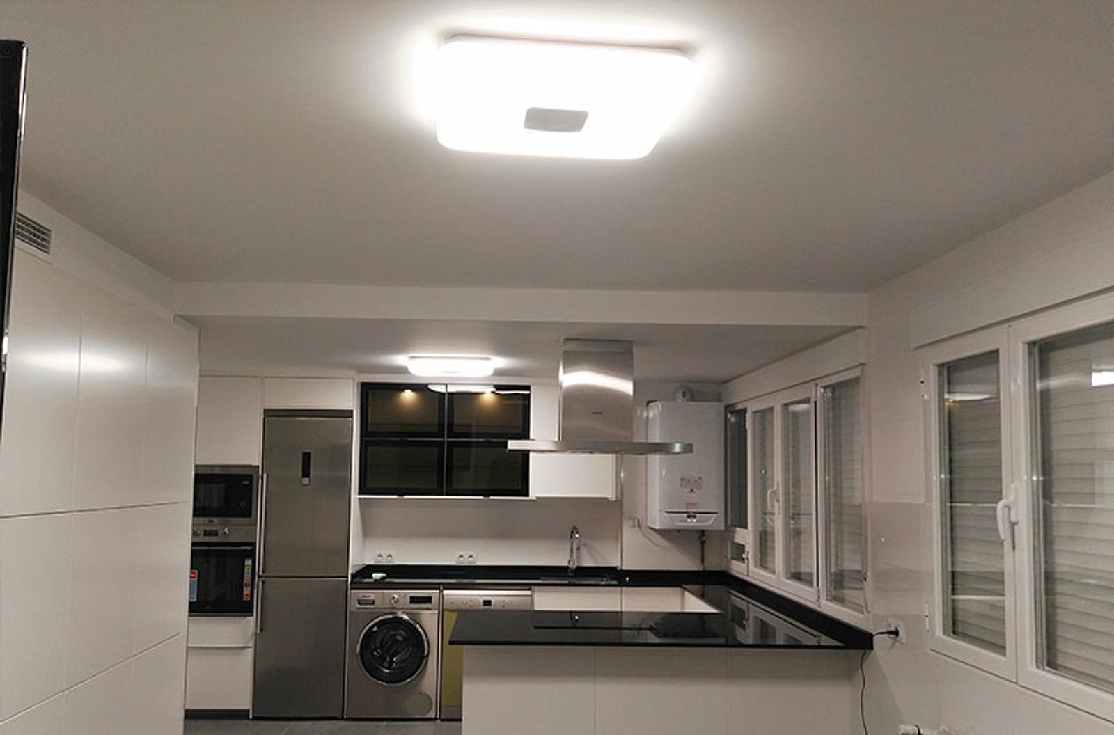 Cocina blanca con encimera negra y electrodomésticos integrados