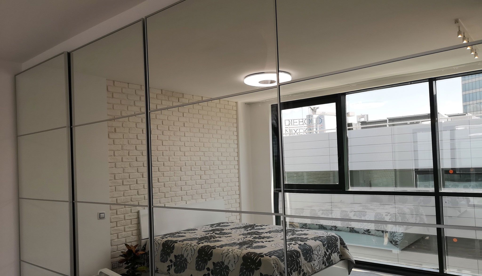 Dormitorio con armario de puertas de espejo de suelo a techo