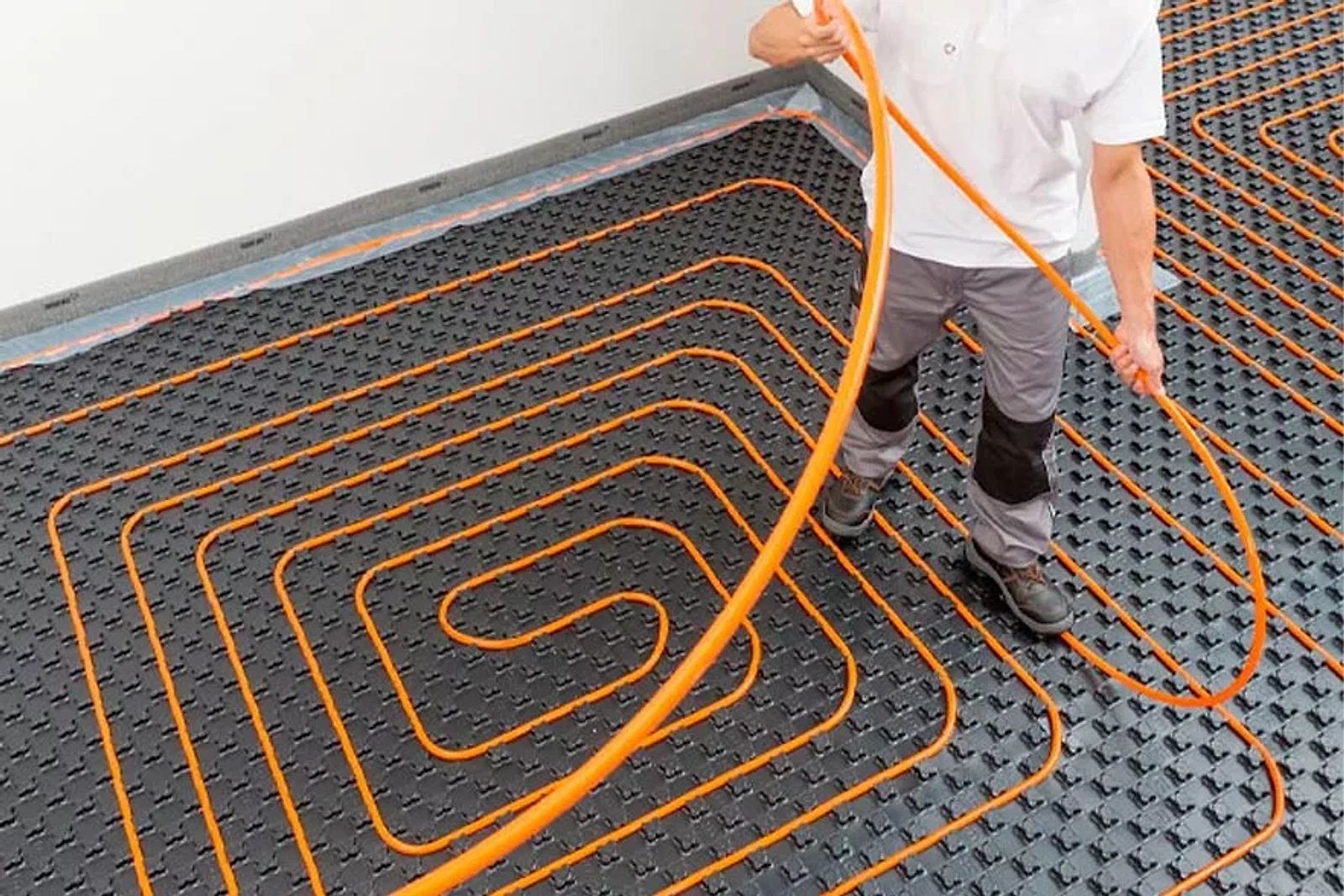 Instalador tendiendo el tubo del suelo radiante sobre el panel aislante
