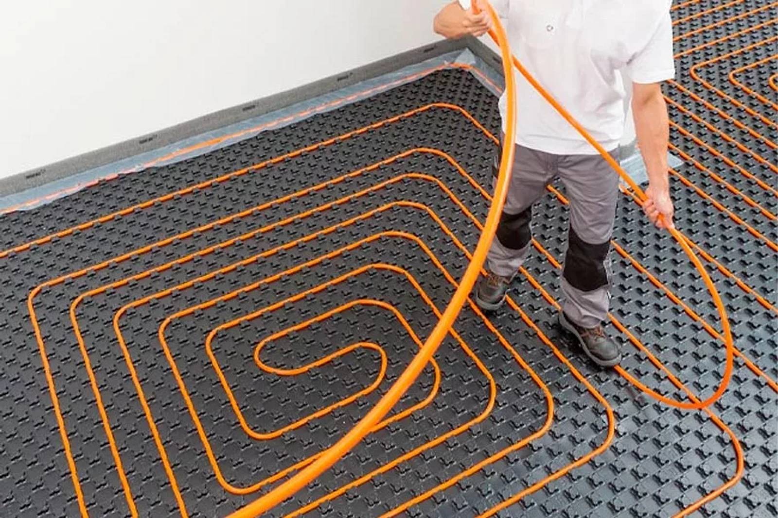Instalador tendiendo el tubo del suelo radiante sobre el panel aislante