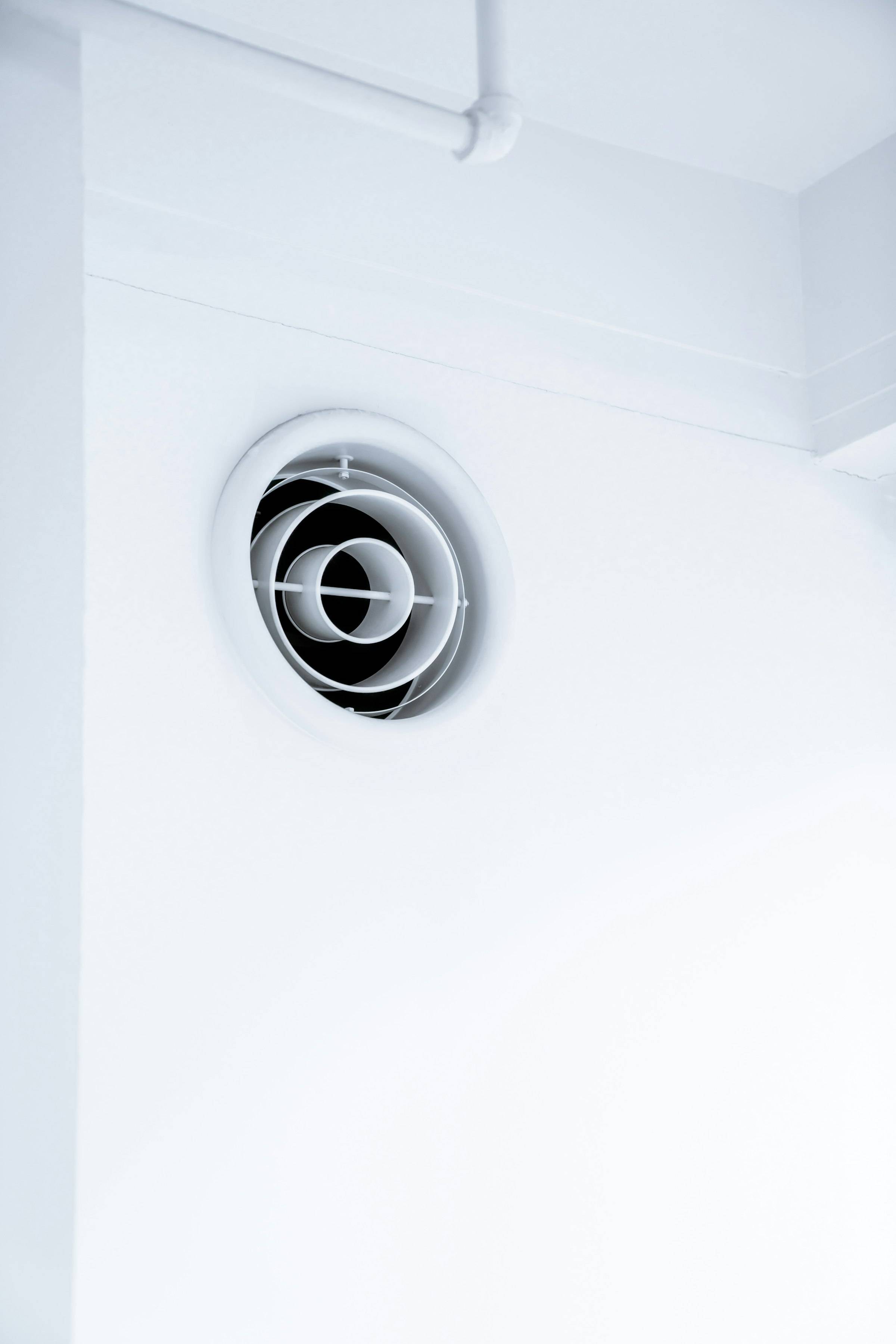 Rejilla redonda de ventilación en una pared blanca